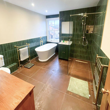 Victorian bathroom with green half-height tiling, freestanding bath by the sash window, green vanity and walk-in shower